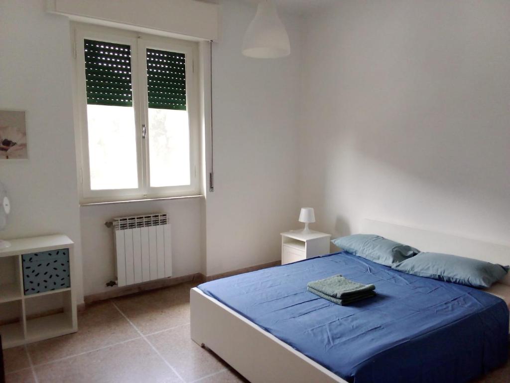 a bedroom with a blue bed and a window at Casa Felci in Tirrenia