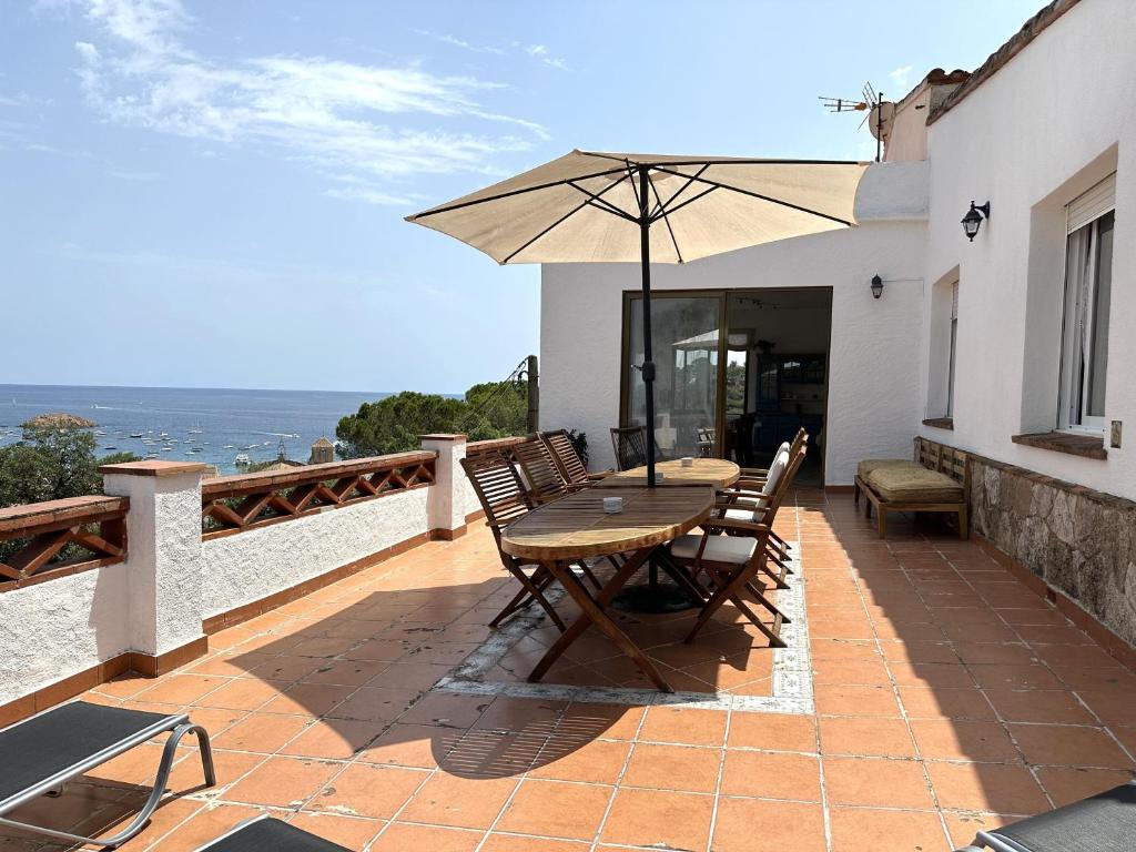een houten tafel en stoelen met een parasol op een patio bij LETS HOLIDAYS Beautiful house sea views in Tossa de Mar