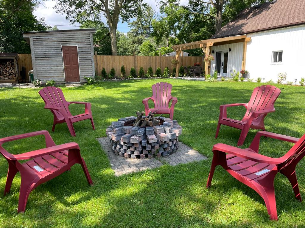 four red chairs sitting around a fire pit in a yard at Cozy Cottage Style House in Kitchener