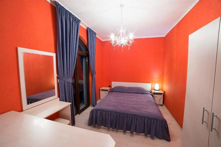um quarto vermelho com uma cama e um espelho em Kris Hotel & Restaurant em Smolyan