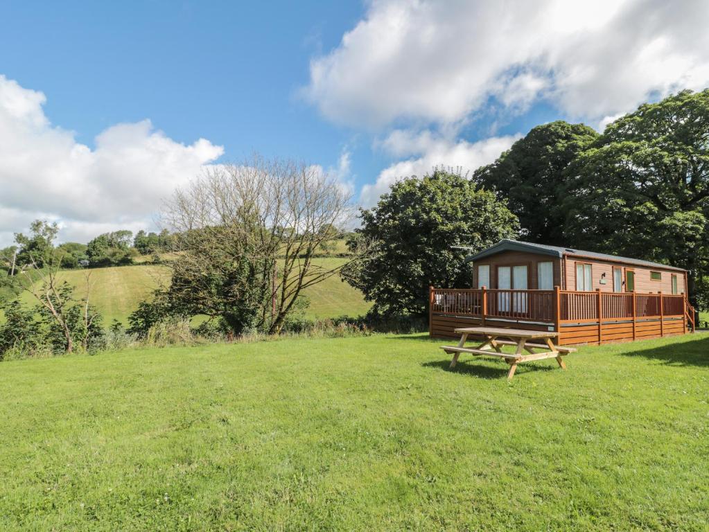 a cabin in the middle of a field with a picnic table at Lodge 11 in Winscombe