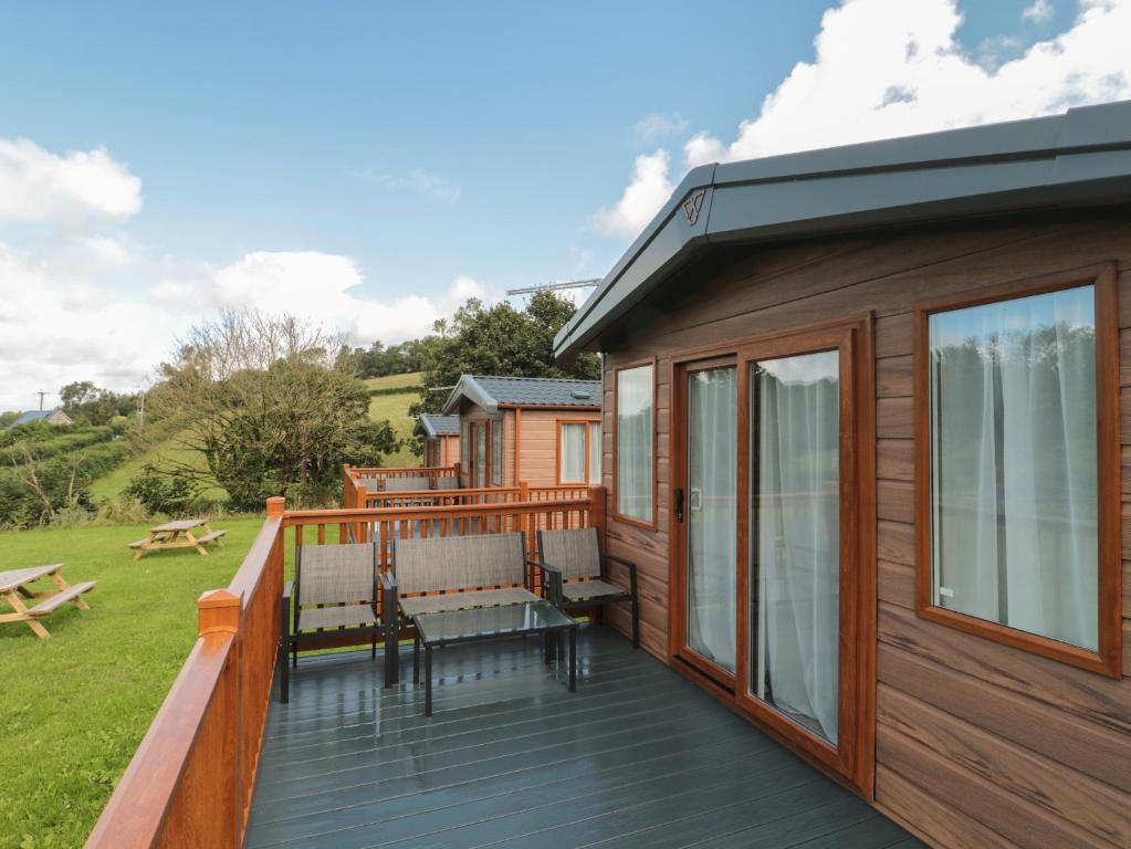 a cabin with a deck with chairs and a table at Lodge 9 in Winscombe