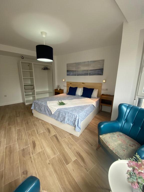 a bedroom with a large bed and a blue chair at ETXIE LA CASA TARASKA in Bermeo