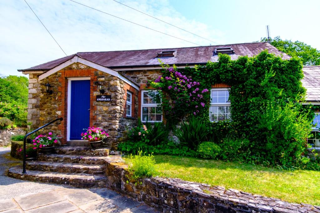 a stone house with a blue door and flowers at Lakeside Cottage in Carmarthen