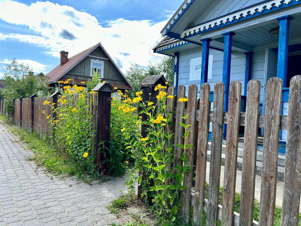 une clôture en bois avec des fleurs jaunes à côté d'une maison dans l'établissement Leśne PoBudki, à Białowieża