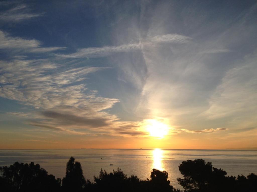 a sunset over the ocean with trees in the foreground at Appartanvilla Magellano in Mondello