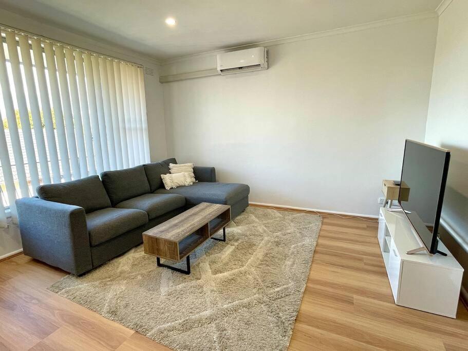 a living room with a couch and a tv at Central Apartment near Dandenong Hospital & Market in Dandenong