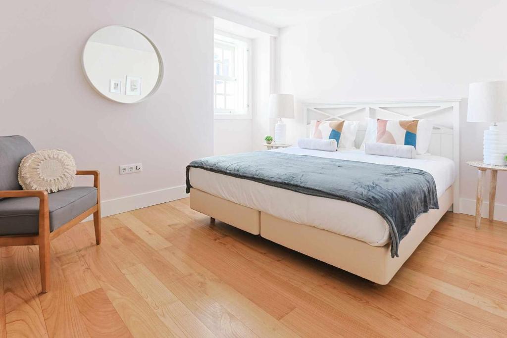 um quarto branco com uma cama grande e uma cadeira em Downtown Charming Apartments Apartamento Ponte em Chaves
