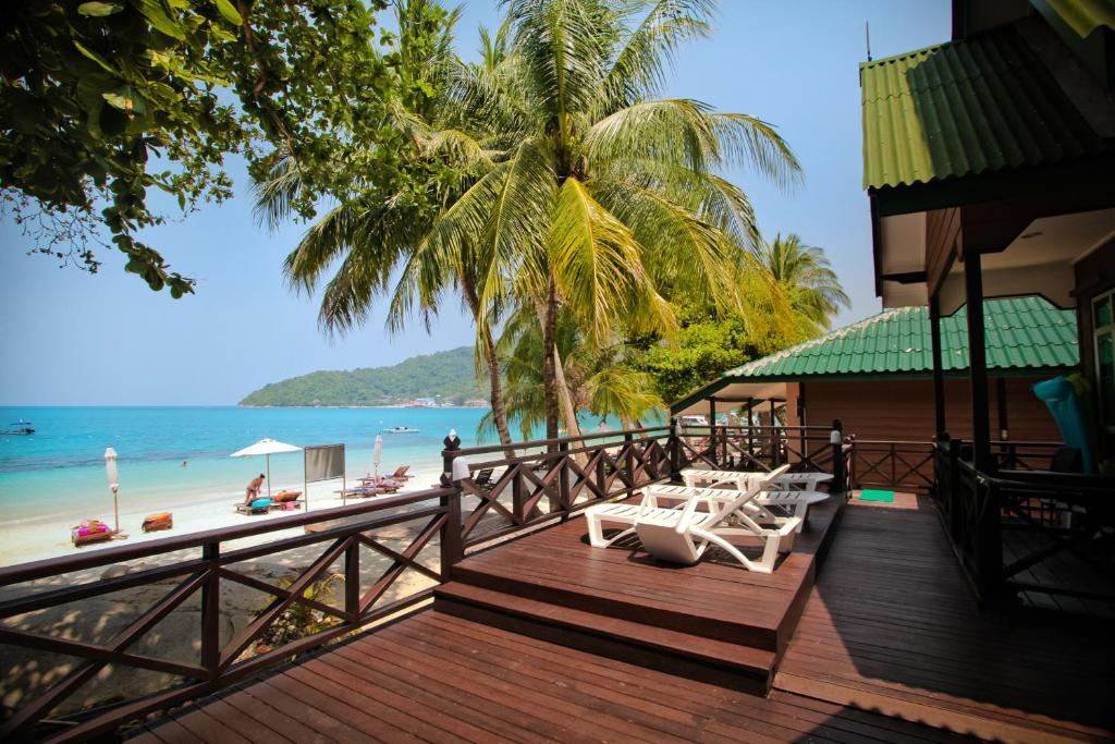 a deck with tables and chairs on the beach at Tuna Bay Island Resort in Perhentian Islands