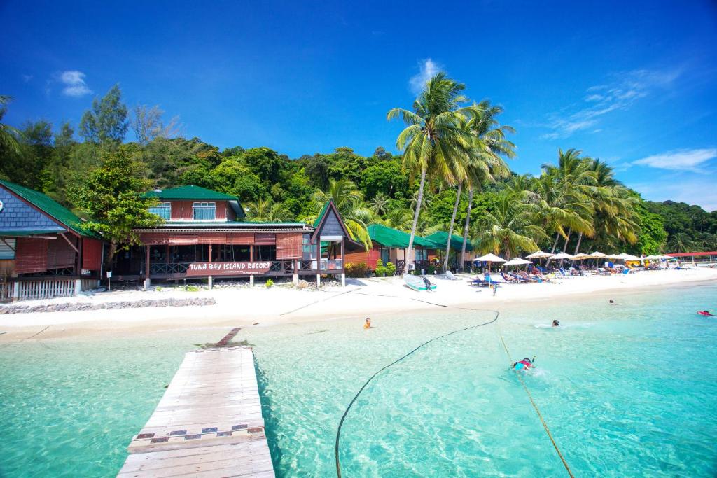 a beach with a pier and people in the water at Tuna Bay Island Resort in Perhentian Islands