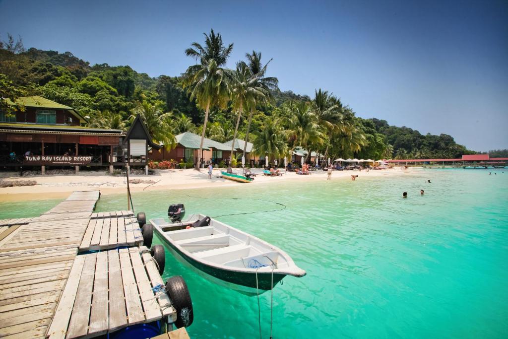 a boat sitting on a dock next to a beach at Tuna Bay Island Resort in Perhentian Islands