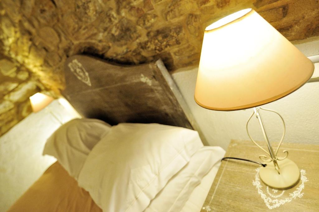 una lámpara en una mesa junto a una cama en Antico Borgo, en Arcevia