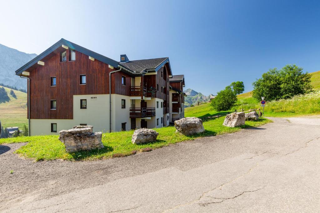 a large barn on a hill next to a road at Aravis in Manigod