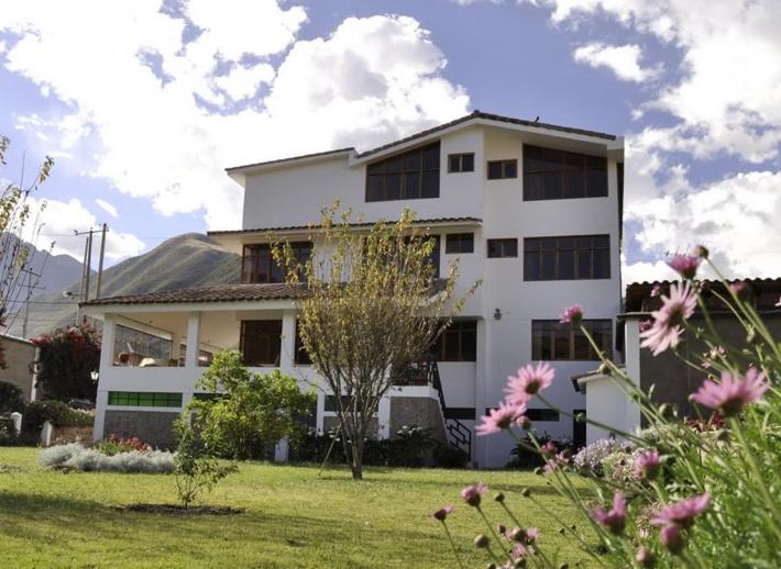 una casa blanca con un patio con flores en Posada Las Tres Marias en Urubamba