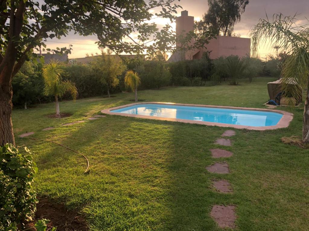 een zwembad in een tuin met een boom bij Villa Moulay Faycal in Marrakesh