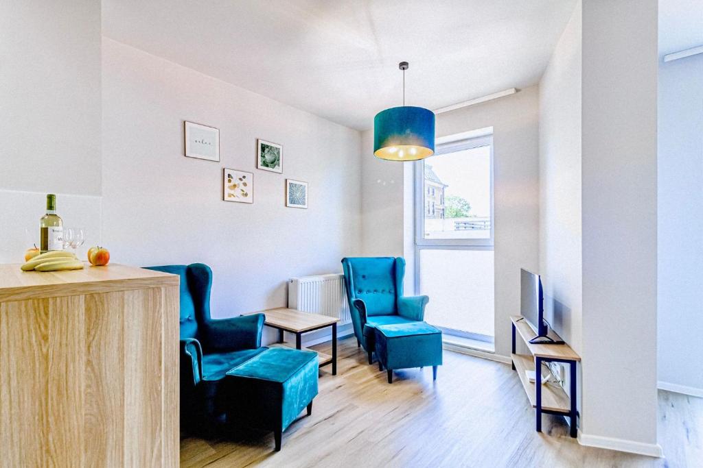 sala de estar con sillas azules, mesa y TV en Apartament Wiedeński de LUX, en Bielsko-Biala