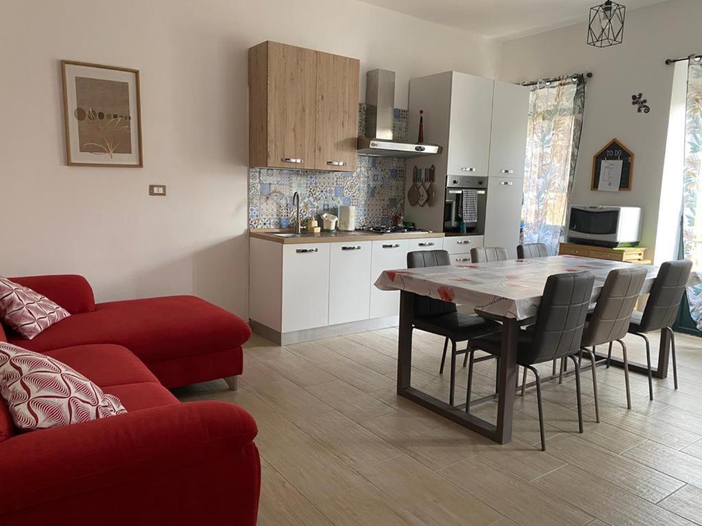 eine Küche und ein Wohnzimmer mit einem Tisch und einem roten Sofa in der Unterkunft La casa sotto il Fortino in SantʼAntìoco