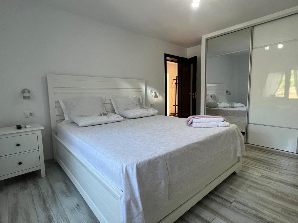 a white bedroom with a large white bed and a mirror at Apartament GEAVIDAN in Eforie Sud