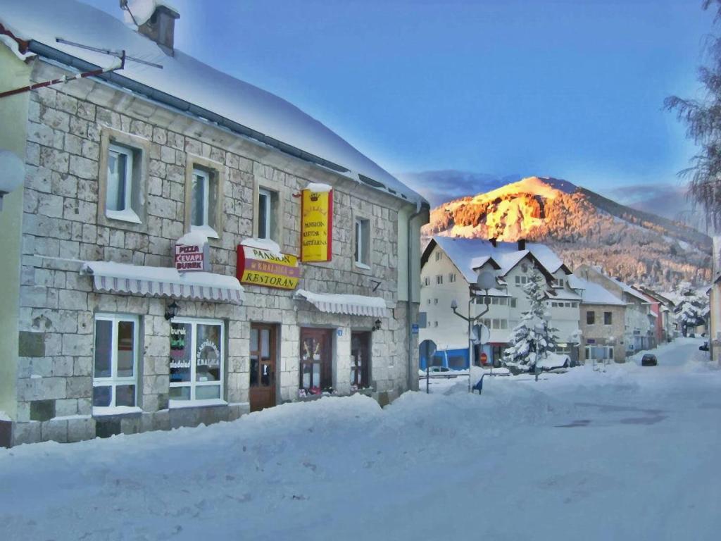 a building in the snow with a mountain in the background at Soba za goste Kraljica 4 in Kupres
