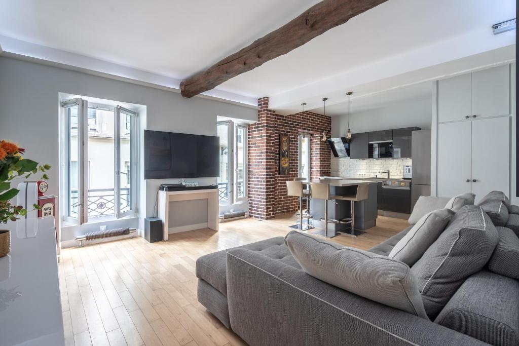 ein Wohnzimmer mit einem Sofa und einer Küche in der Unterkunft Room in Apartment - Cosy place in the Hear of Paris in Paris