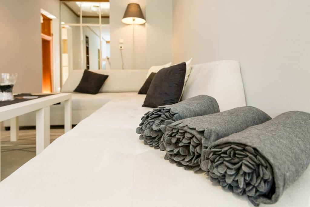 a white bed with gray pillows on top of it at 95sqm 7min Center 2bedroom Gas heating Marble Wc 2 SmartTv in Thessaloniki