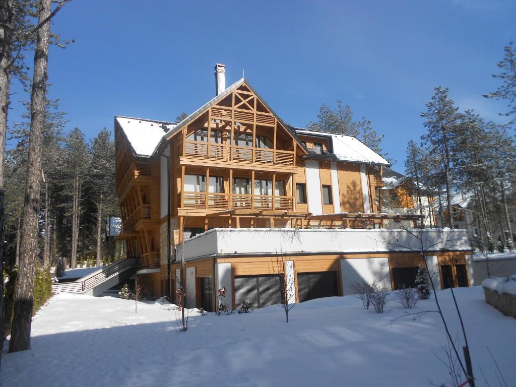 a large wooden house in the snow at Apartment MiMa in Zlatibor