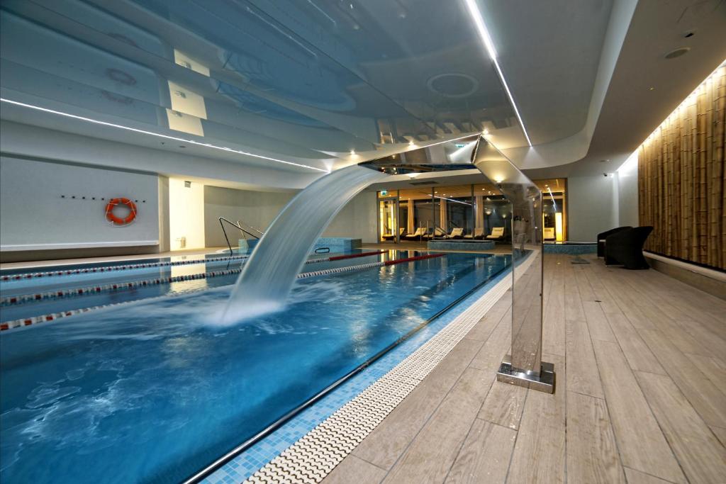 a swimming pool with a water fountain in a building at Hotel Bażantowo Sport in Katowice