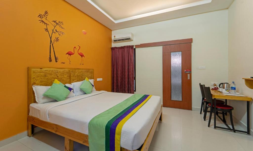 Treebo Trend Eden Park Hotel 3 Km From Puducherry Airport في بونديتْشيري: غرفة نوم بسرير ومكتب وطاولة