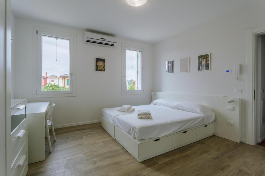 a white bedroom with a bed and two windows at Yourbanflat White River 2 in Padova