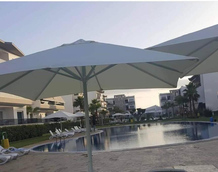 una sombrilla blanca grande junto a la piscina en Appartement à Blanca Beach., en Casablanca