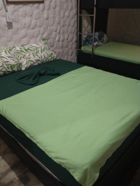 a bedroom with two beds with green sheets at Cabaña El Tucan in Minca