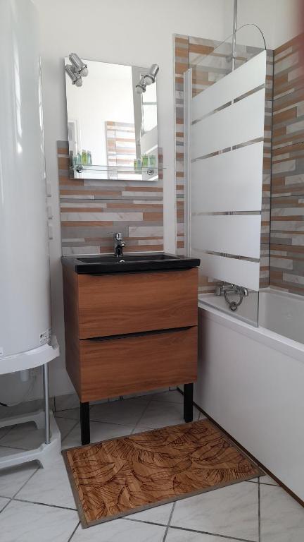 Un baño con lavabo, bañera y espejo. en les galipes, en Hautvillers