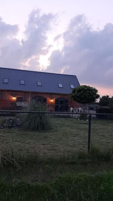 a building in a field with a tree in front of it at appartement in authentiek koetshuis met bedstee in Moerstraten
