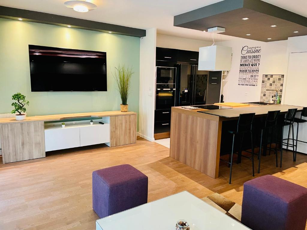 Il comprend une cuisine avec une télévision et un bar avec des tabourets violets. dans l'établissement Spacious Cozy Apartment close Paris & Flea Market at St Ouen, à Saint-Ouen