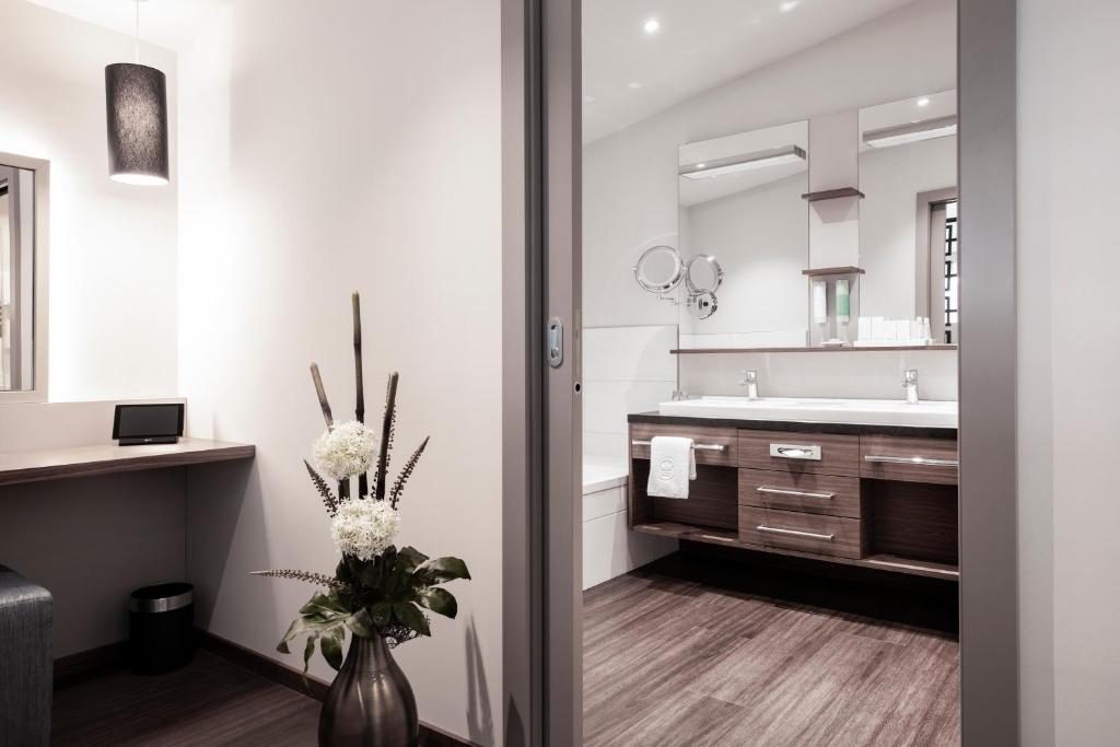 un bagno con lavandino e vaso con fiori di Nuhr Medical - Hotel & Restaurant a Senftenberg