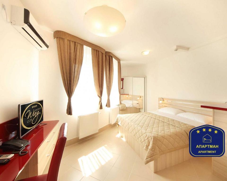 a bedroom with a bed and a desk and a window at Wing Club Dajana in Jagodina