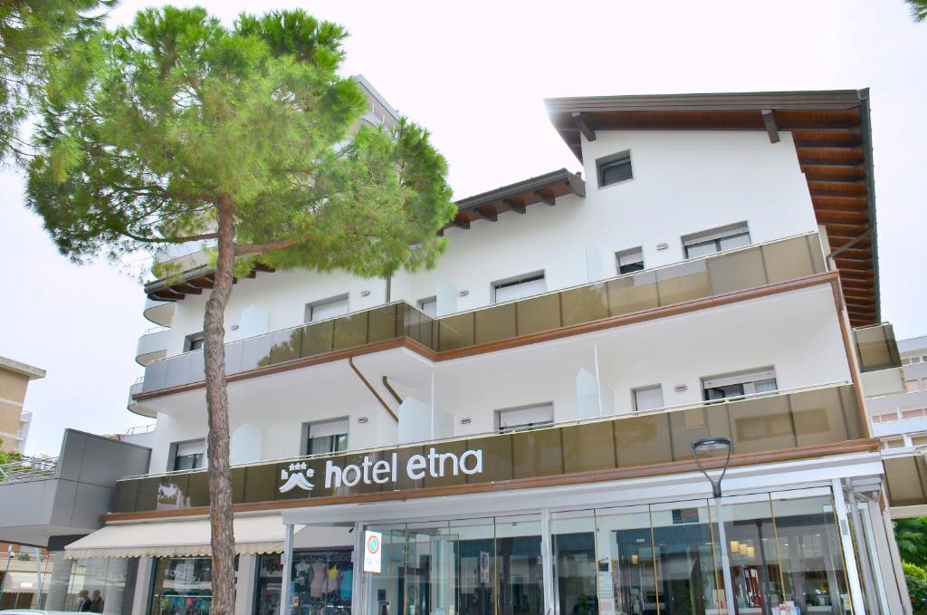 a building with a hotel and a tree at Hotel Etna in Lignano Sabbiadoro