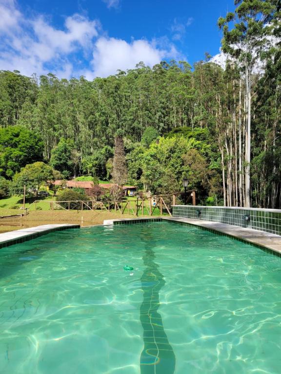 einen Pool mit Bäumen im Hintergrund in der Unterkunft A Casa da Fazenda in Santo Antônio do Pinhal