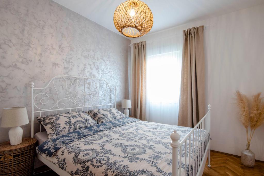 een slaapkamer met een wit bed en een kroonluchter bij Apartman Karla in Sinj