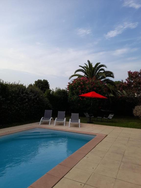 une piscine avec deux chaises et un parasol dans l'établissement Villa Piscine Golf Tennis Méditerranée, à Baillargues