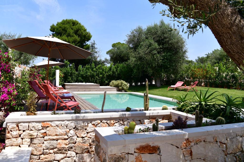 basen z parasolem, krzesłami i stołem w obiekcie IL TRULLO BIANCO - Country House & SPA w mieście Castellana Grotte