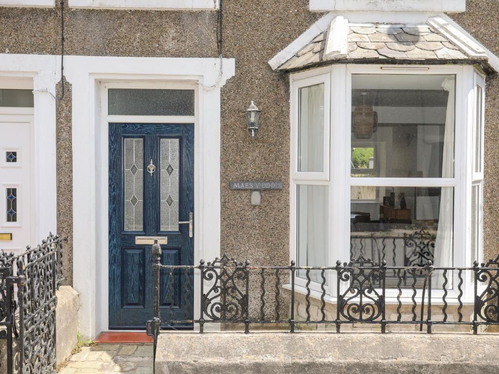 una casa con una puerta azul y una ventana en Maes Y Ddol en Pwllheli