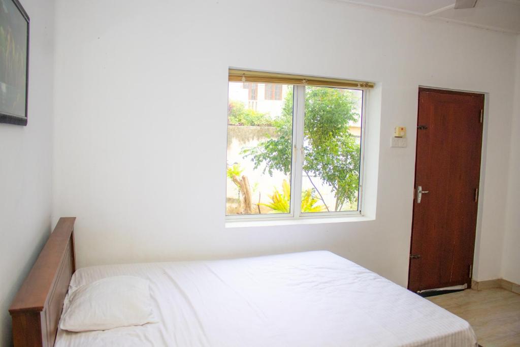 um quarto com uma cama e uma janela em Mount Guest em Karagampitiya