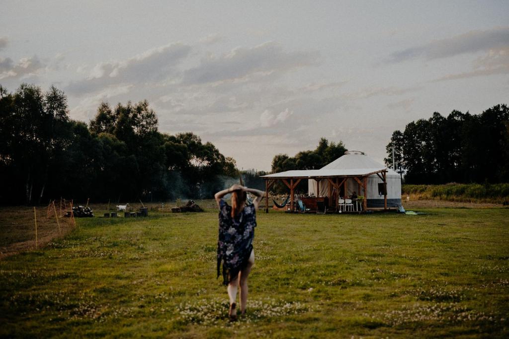a woman in a dress walking in a field with a tent at Szczere Pole in Karpacz