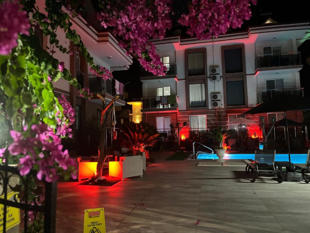 un patio de un edificio por la noche con flores rosas en kerim apart tatil evleri, en Fethiye