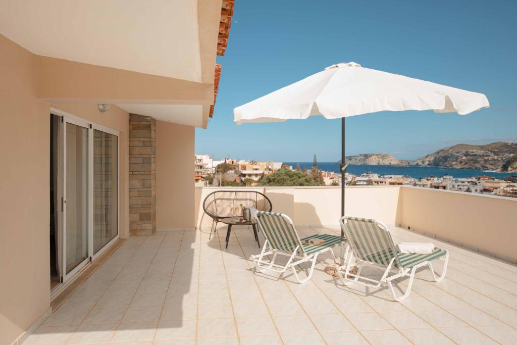 a balcony with two chairs and an umbrella at Villa Melenia 2 in Agia Pelagia