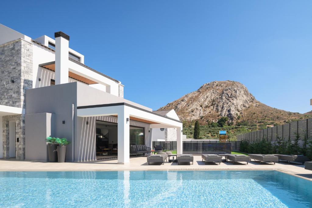 a villa with a swimming pool and mountains in the background at Monti Luxury Villa, Close to South Crete beaches, By ThinkVilla in Lefkogeia