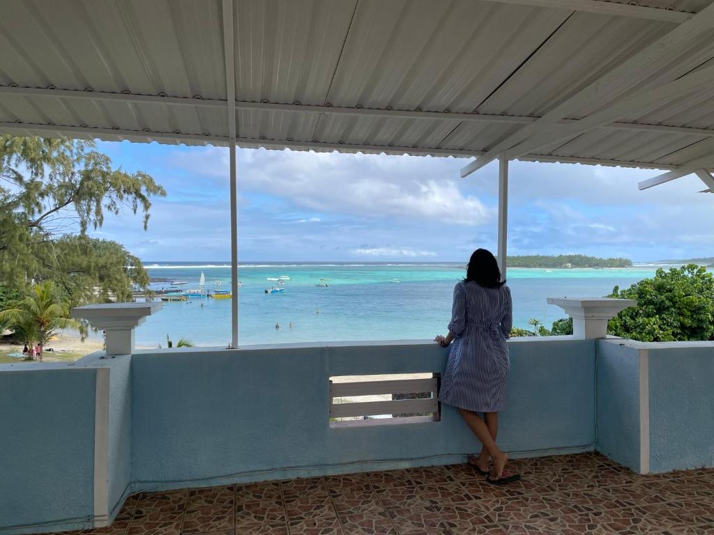 uma mulher sentada num banco a olhar para o oceano em Villa de la Playa em Blue Bay