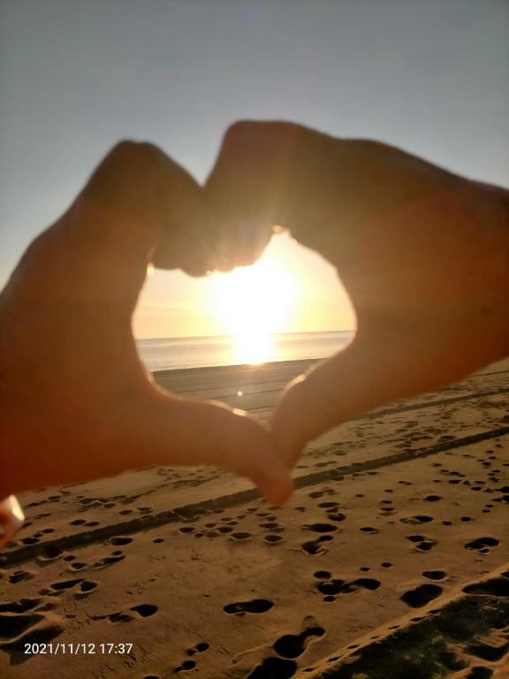 uma pessoa que faz uma forma de coração com o pôr do sol no fundo em Estudio em Torrox Costa