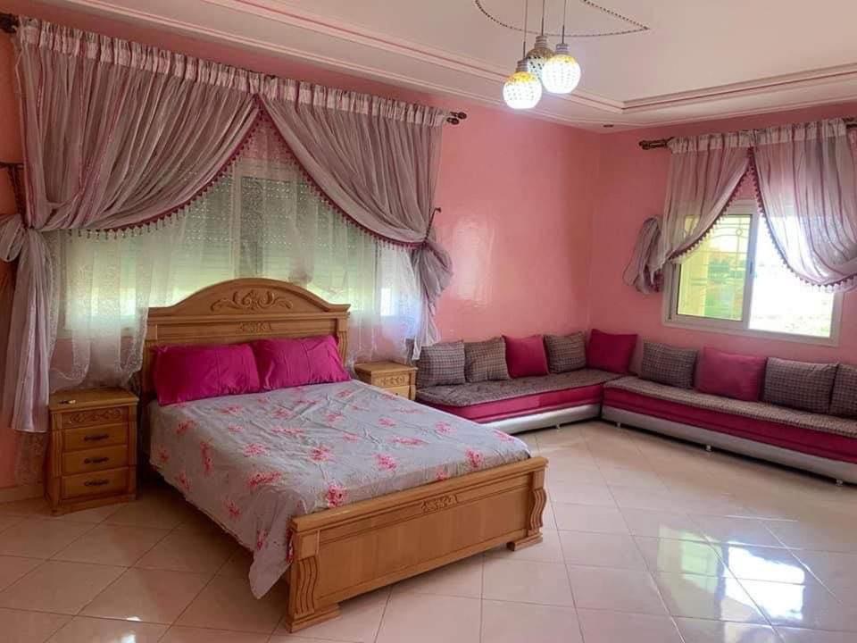 een slaapkamer met roze muren en een bed en een bank bij Stunning 3-Bed Villa in Fes near fes sais airport in Fès